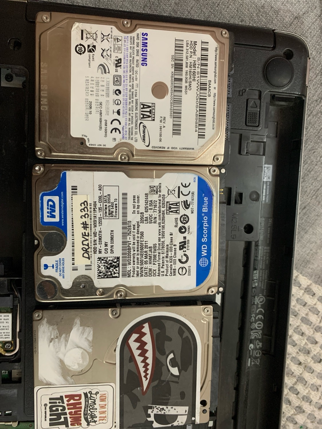 Three laptop hard drives, one covered in stickers